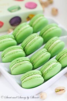 green macaroons and almonds on a white tray