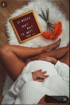 a woman laying on the floor with her legs crossed next to a sign that says, st weeks don't wait to meet you