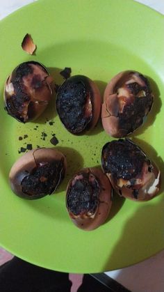 a green plate filled with chocolate covered donuts on top of a table next to a person