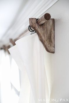 the curtain rod is attached to the wall with a wooden hook on it's side