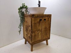 a wooden cabinet with a white bowl on top and a plant growing out of it