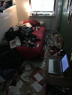 a messy room with a laptop on the bed