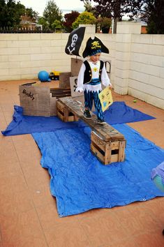 a man dressed as a pirate jumping over a wooden pallet on a blue tarp