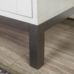 a close up of a white dresser on a wooden floor with a rug underneath it