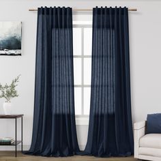 a living room with a couch, chair and window covered in dark blue sheer curtains