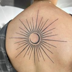 the back of a woman's shoulder with a sun tattoo on it