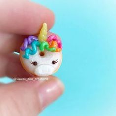 a tiny unicorn - shaped bead is being held by someone's hand