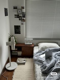 a bed with a laptop on top of it next to a lamp and some books