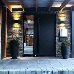 a black door with two planters on each side and lights above the entrance to a house