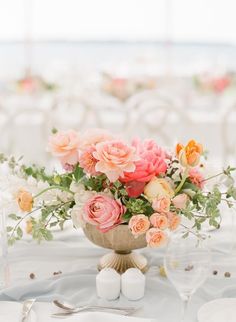 an arrangement of flowers in a vase on a table with white linens and silverware