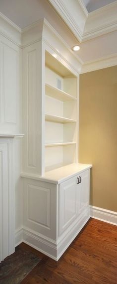 an empty room with white bookcases and wood floors