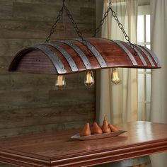 a wooden table topped with three pears under a light fixture hanging from the ceiling