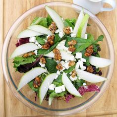 an apple and walnut salad in a glass bowl on top of a wooden cutting board