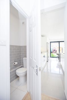 an open door leading to a white bathroom