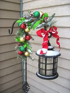 a lamp post decorated with christmas decorations and ribbon hanging from it's top, next to a lantern