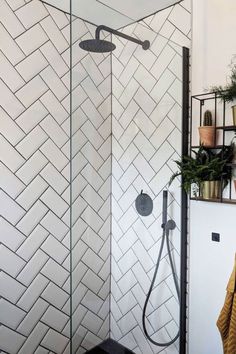 a shower with white tile and black fixtures