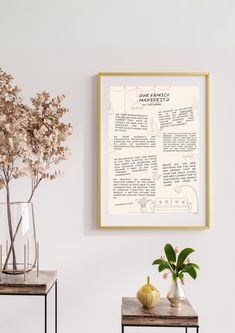 two tables with vases and flowers on them in front of a white wall that has a framed poster above it