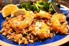 a blue plate topped with shrimp and rice next to broccoli