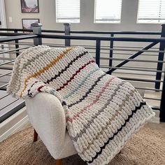 a chair with a blanket on top of it in front of some stairs and windows