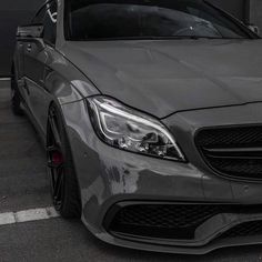 the front end of a grey mercedes benz coupe parked in a parking lot next to a building