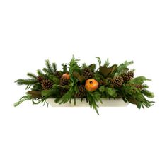 an arrangement of pine cones, ferns and oranges in a white planter on a white background