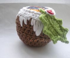 a crocheted basket with a green and white decoration on the top, sitting on a table