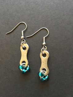 two pairs of gold and turquoise beaded earrings on a black surface with silver hooks