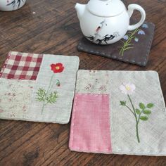 three coasters with different designs on them sitting on a table next to a tea pot