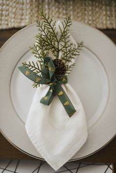 a white plate topped with a napkin and pine cone