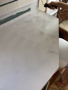 a person using a drill to paint the top of a table