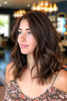 Woman with wavy brown hair smiling softly in a well-lit indoor setting. Level 5 Brown Hair With Lowlights, Brunette Glossy Hair, Brunette Haircut Round Face, Medium Brown Hair With Face Framing Highlights, Dark Chocolate Short Hair, Shirt Brunette Hair, Deep Espresso Hair Color, Dark Brown Haircut Ideas, Cool Undertone Brown Hair