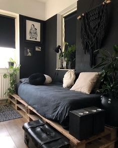 a bedroom with black walls and wooden pallets on the floor, potted plants