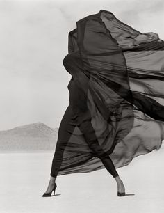 a black and white photo of a woman in high heels with her dress blowing in the wind