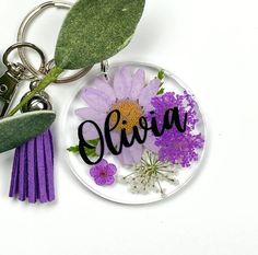 a keychain with a flower and the word alvia written in black on it