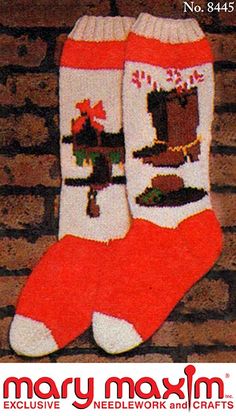 a pair of red and white socks with christmas decorations on them, sitting next to a brick wall