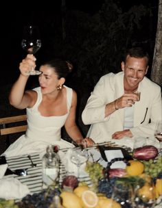 a man and woman sitting at a table holding wine glasses