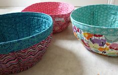 three colorful baskets are sitting on the floor