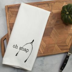 a kitchen towel with the words oh snap on it next to a knife and pumpkin