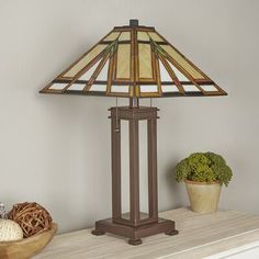 a lamp sitting on top of a wooden table next to a basket and potted plant