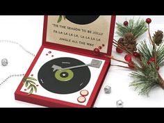 a christmas card with a record player and pine cones on the table next to it