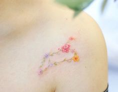 a close up of a woman's shoulder with flowers painted on the back of it