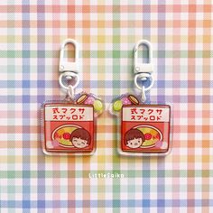 two little tags with japanese characters are on a checkered tablecloth, one has a clip and the other has a clip