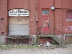 an old brick building with graffiti on the door and steps leading up to it's entrance