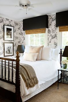 a white bed sitting in a bedroom next to a window with black and white wallpaper