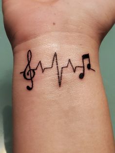 a wrist tattoo with musical notes on it