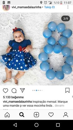 a baby laying on top of a white blanket next to blue balloons