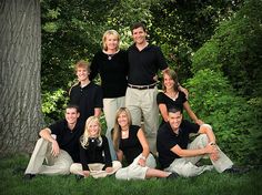 a group of people posing for a photo in front of a tree and grass area