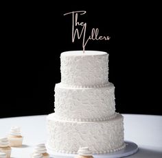 a white wedding cake and cupcakes on a table