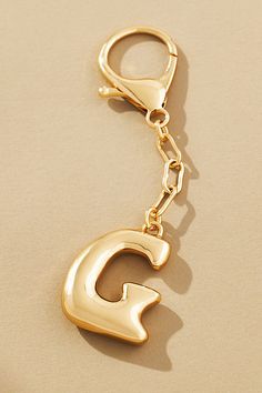 a gold keychain with the letter g on it's front and back ends