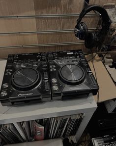 two decks of dj equipment sitting on top of a table next to headphones and cds